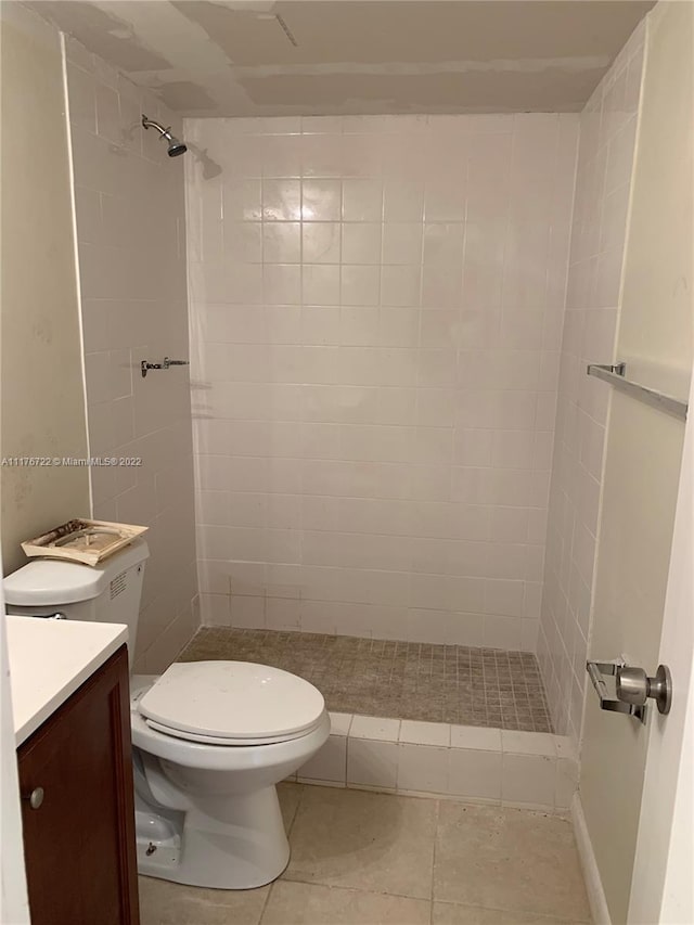 bathroom featuring tile patterned floors, vanity, toilet, and tiled shower