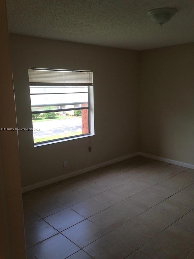 spare room with a textured ceiling and light tile patterned flooring