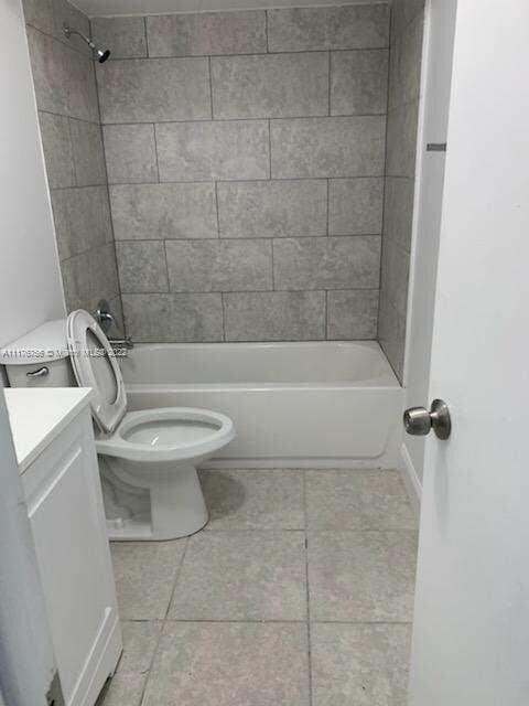 full bathroom with tiled shower / bath, tile patterned floors, vanity, and toilet