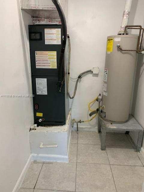 utility room featuring heating unit and gas water heater