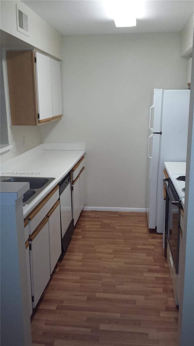 kitchen featuring white dishwasher, sink, stainless steel range, dark hardwood / wood-style flooring, and white cabinetry