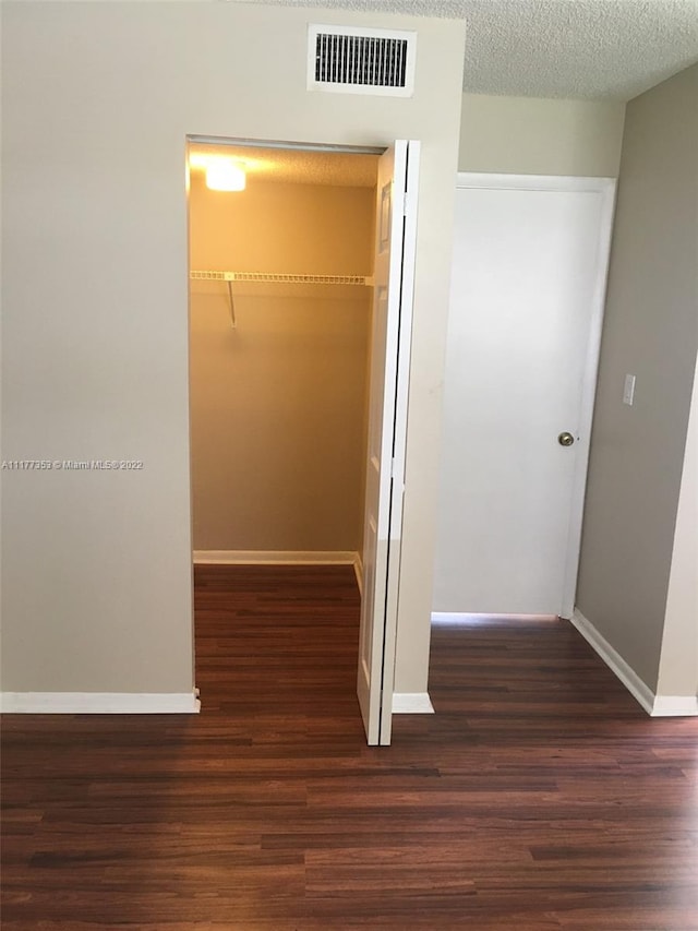 corridor featuring a textured ceiling and dark hardwood / wood-style floors