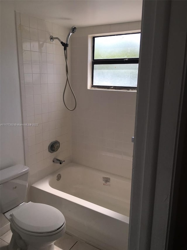 bathroom with tile patterned flooring, tiled shower / bath, and toilet