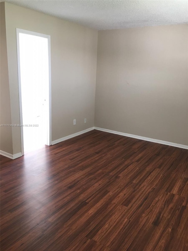 unfurnished room with dark hardwood / wood-style flooring and a textured ceiling