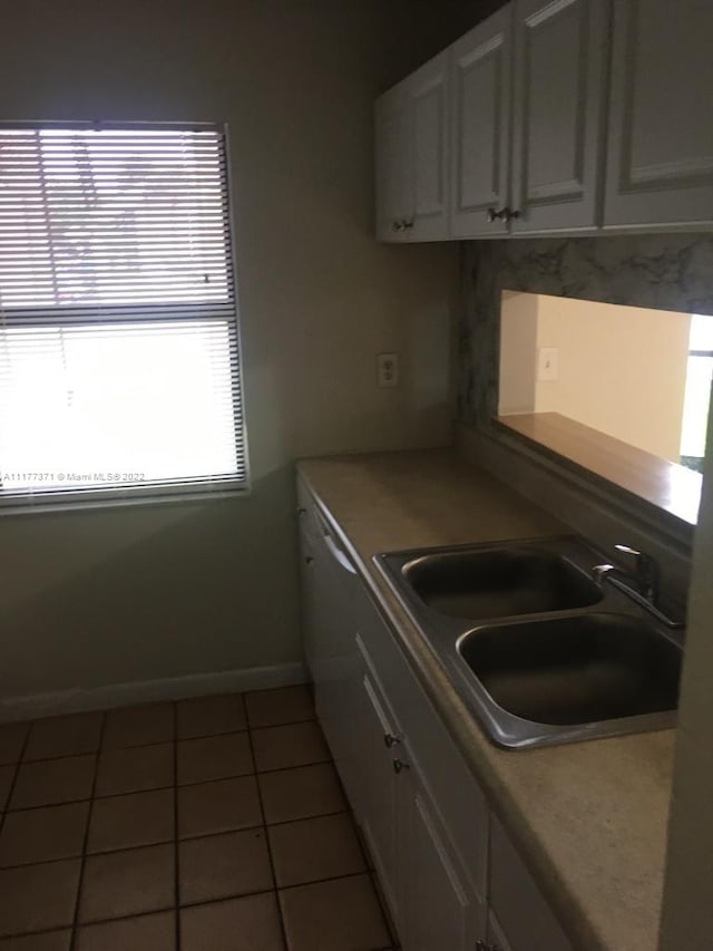 kitchen featuring white cabinets, dishwasher, dark tile patterned floors, and sink