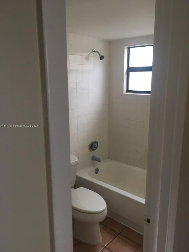 bathroom featuring tile patterned floors, tiled shower / bath, and toilet