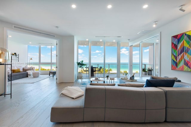 living room featuring light hardwood / wood-style floors, expansive windows, and a water view