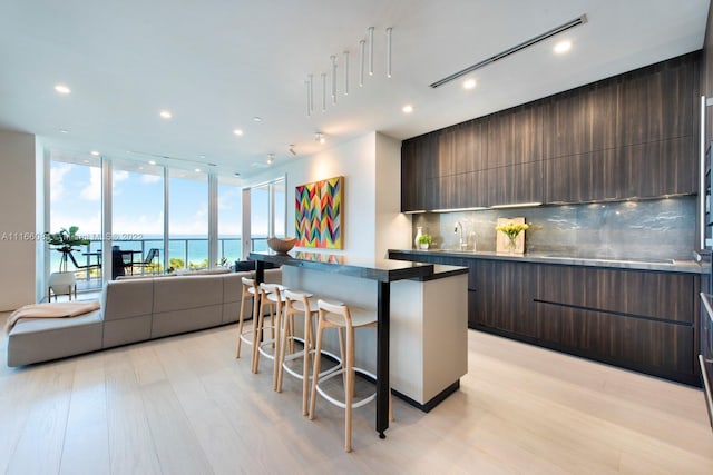 kitchen with a kitchen bar, a center island, light hardwood / wood-style flooring, and a water view