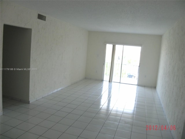 tiled empty room featuring a textured ceiling