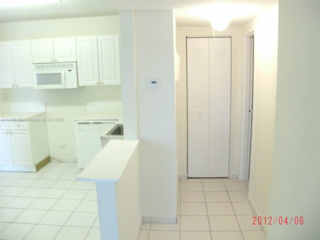 kitchen with white cabinets, white appliances, and light tile patterned flooring