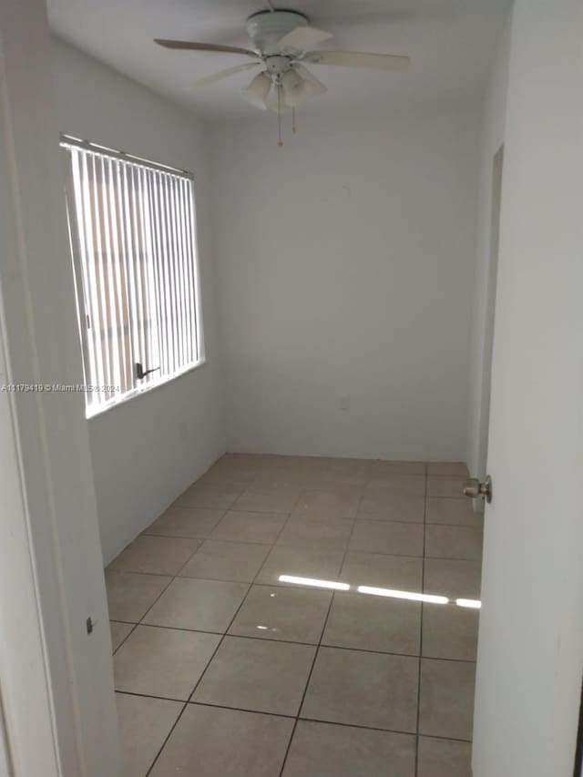 spare room with ceiling fan and light tile patterned floors