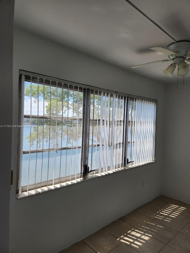 unfurnished room featuring tile patterned flooring, ceiling fan, and a water view