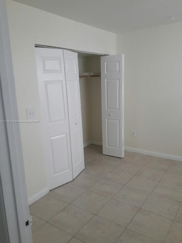 unfurnished bedroom featuring light tile patterned floors and a closet