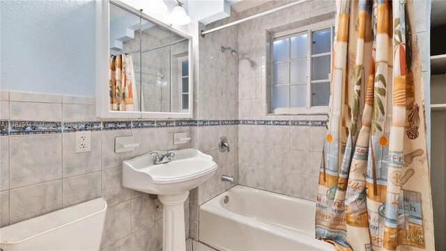 bathroom with shower / bath combo with shower curtain, tile walls, and toilet