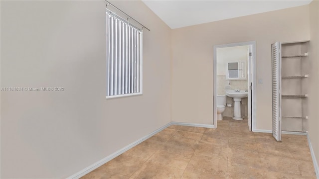 unfurnished bedroom with ensuite bath and light tile floors