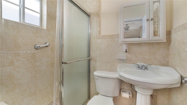 bathroom featuring tile walls, toilet, and a shower with door