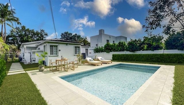 rear view of house with a patio, a fenced in pool, and a yard