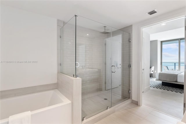 bathroom with independent shower and bath, tile floors, and a water view