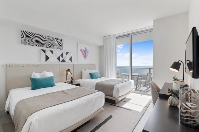 bedroom featuring a water view, expansive windows, and access to outside