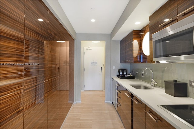 kitchen with backsplash, black electric cooktop, sink, and light tile flooring