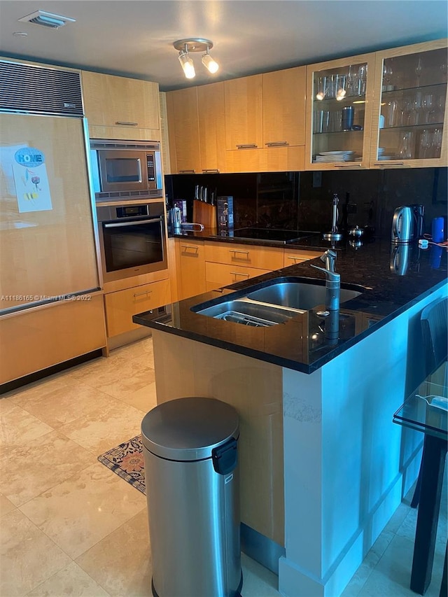 kitchen with built in appliances, light brown cabinets, tasteful backsplash, and kitchen peninsula