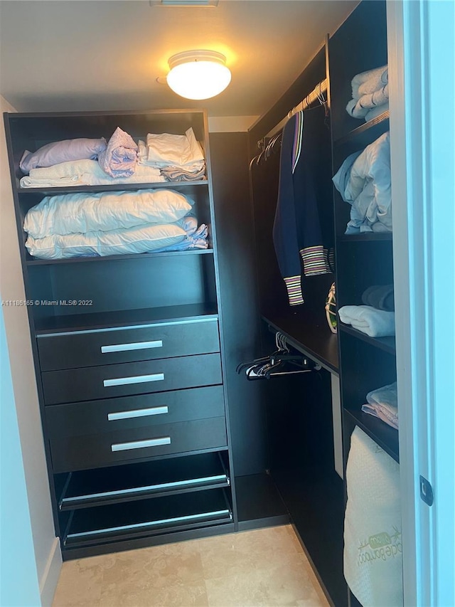 spacious closet with dark tile flooring