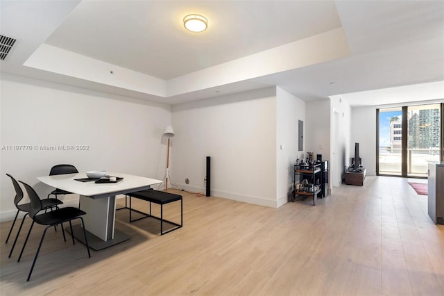 dining space featuring a tray ceiling and light wood-type flooring