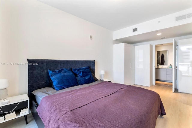 bedroom with light hardwood / wood-style floors and connected bathroom