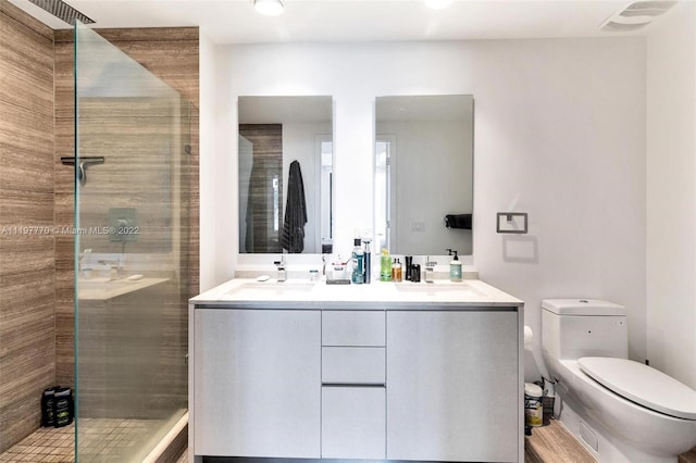 bathroom with walk in shower, toilet, and double sink vanity