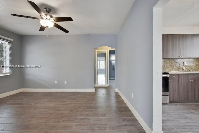 tiled empty room featuring ceiling fan and sink