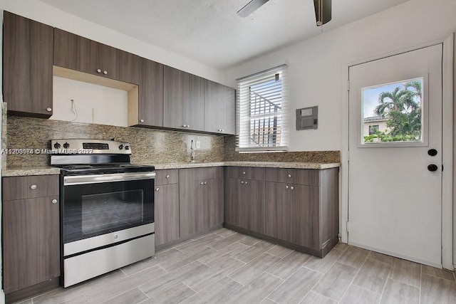 kitchen featuring ceiling fan, light stone counters, stainless steel range with electric stovetop, tasteful backsplash, and dark brown cabinetry