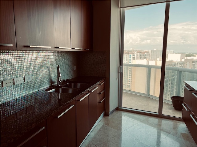 kitchen with dark stone countertops, tasteful backsplash, sink, and light tile floors