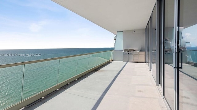 balcony featuring a water view and an outdoor kitchen