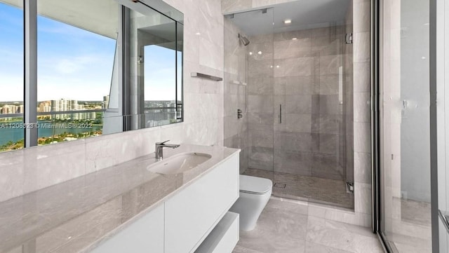 bathroom featuring toilet, large vanity, a shower with door, a water view, and tile walls