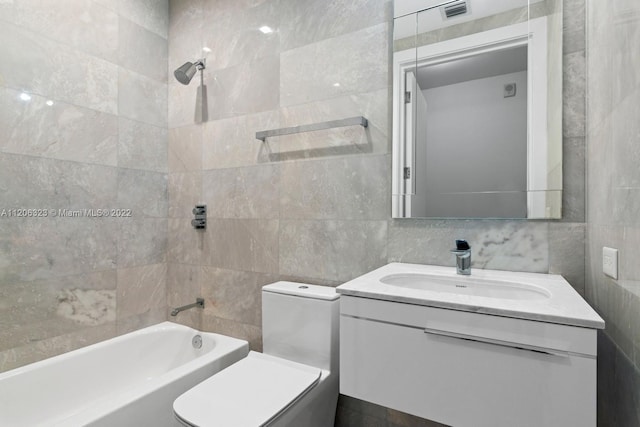 full bathroom featuring tiled shower / bath, tile walls, toilet, and vanity