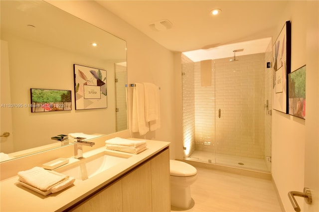 bathroom featuring walk in shower, vanity with extensive cabinet space, and toilet