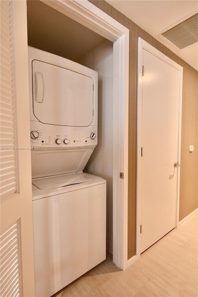 laundry room featuring stacked washer / dryer and light wood-type flooring