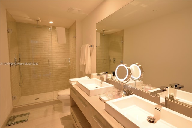 bathroom featuring toilet, double vanity, and tiled shower