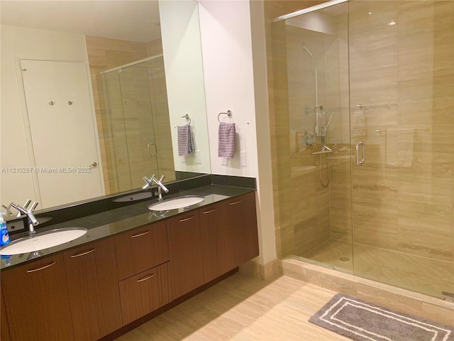 bathroom with double sink vanity, a shower with shower door, and hardwood / wood-style floors