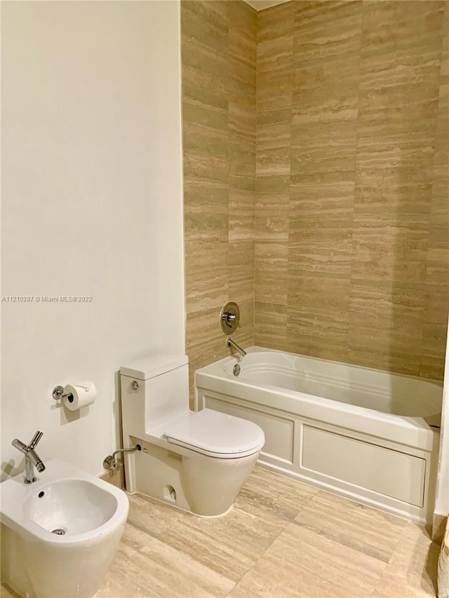 bathroom with a bidet, toilet, and tiled shower / bath