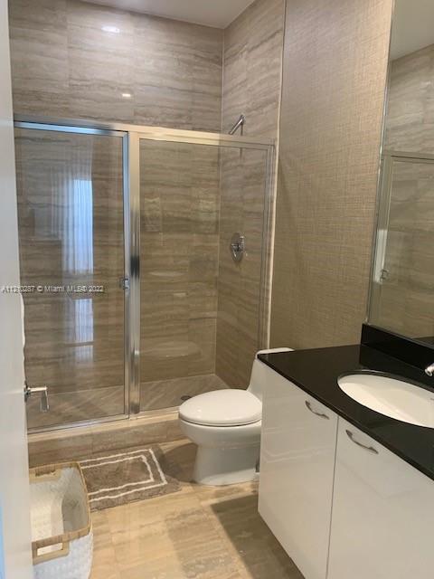 bathroom featuring an enclosed shower, toilet, vanity, and tile flooring