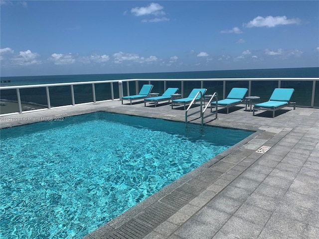 view of pool with a water view and a patio