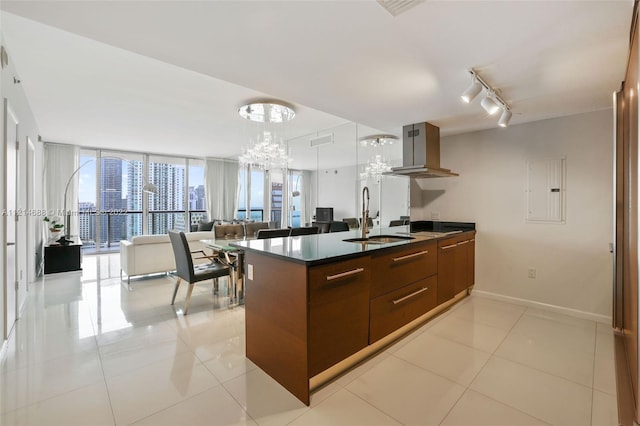 kitchen featuring island range hood, rail lighting, sink, a wall of windows, and an inviting chandelier