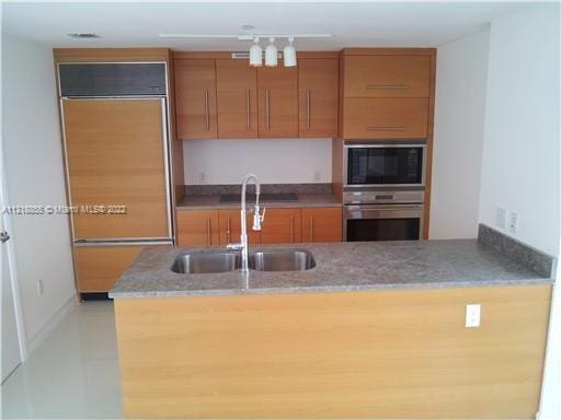 kitchen featuring oven, black microwave, sink, and kitchen peninsula