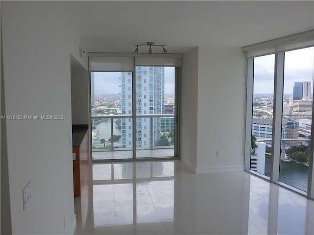 empty room with a wall of windows, a water view, and plenty of natural light