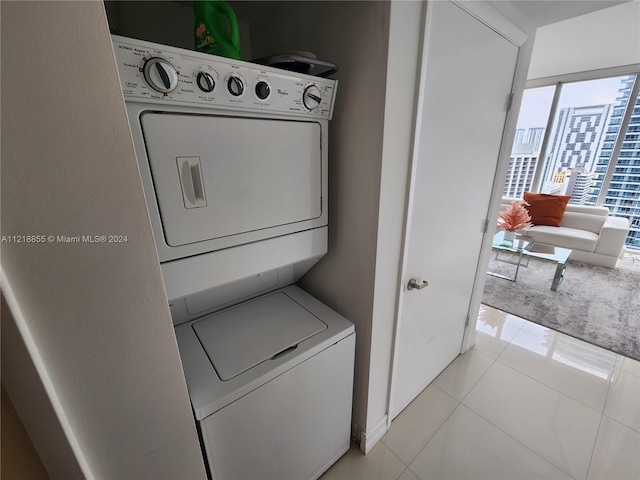 laundry area with light tile patterned flooring and stacked washing maching and dryer