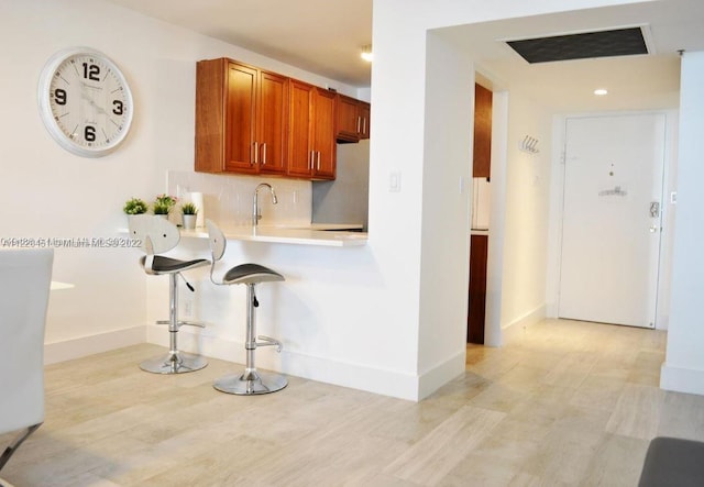 kitchen with tasteful backsplash, a kitchen breakfast bar, sink, and refrigerator