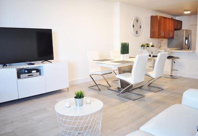 dining space with sink and light hardwood / wood-style flooring