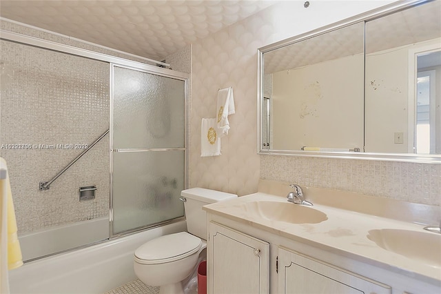 full bathroom featuring combined bath / shower with glass door, toilet, and dual vanity