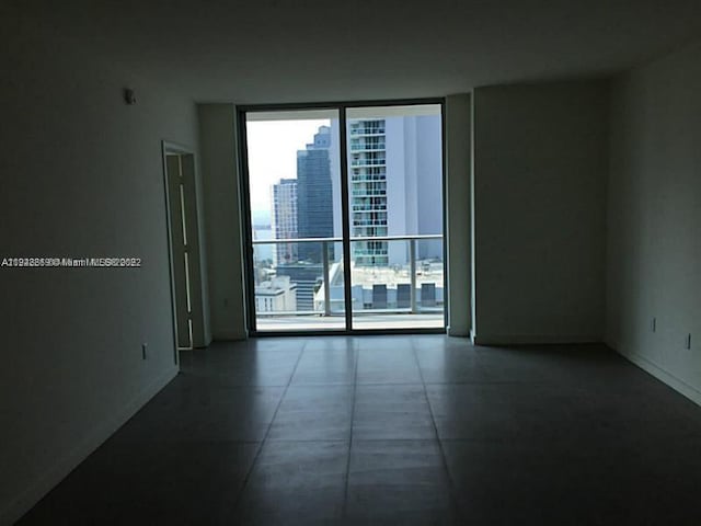 tiled spare room featuring plenty of natural light and floor to ceiling windows